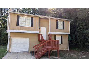 Tan two-story house with red stairs and attached garage at 5300 Forest Downs Ln, Atlanta, GA 30349