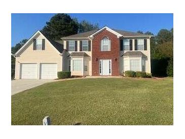 Two-story brick and siding house with a two-car garage and manicured lawn at 2608 Downing Park Se Dr, Conyers, GA 30094
