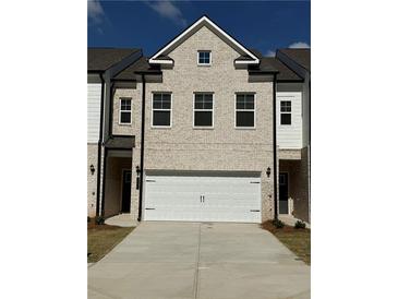 Brick townhouse with a two-car garage and landscaping at 8194 Tiger Way, Riverdale, GA 30247