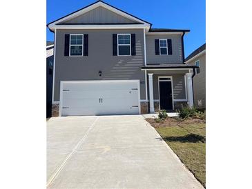 Two-story house with gray siding, white garage door, and landscaping at 11963 Conrad Cir, Hampton, GA 30228