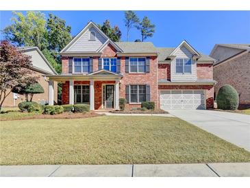Brick house with a two-car garage and landscaping at 3191 Lake Mcginnis Dr, Suwanee, GA 30024