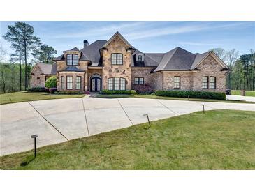 Large brick home with stone accents, a circular driveway, and manicured lawn at 187 Fontaine Sw Rd, Mableton, GA 30126