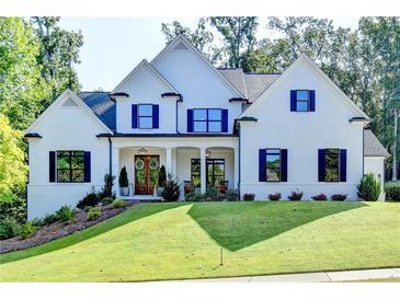 Two story home with white exterior, navy shutters, and lush landscaping at 5855 Windjammer Pt, Cumming, GA 30041