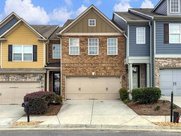 Brick townhome with two-car garage, landscaping, and a paved driveway at 2397 Sardis Chase Ct, Buford, GA 30519
