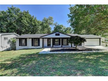Charming ranch house with white brick exterior, black trim, and a manicured lawn at 1365 Renee Dr, Decatur, GA 30035