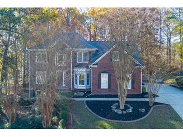 Charming two-story brick home nestled among trees with a landscaped front yard at 2001 Towne Lake W Hls, Woodstock, GA 30189