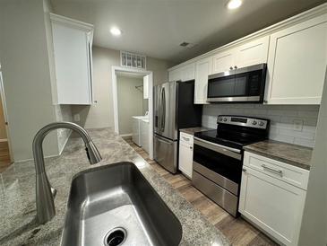 Modern kitchen with stainless steel appliances, granite countertops, and white cabinetry at 425 Warm Springs Cir, Roswell, GA 30075