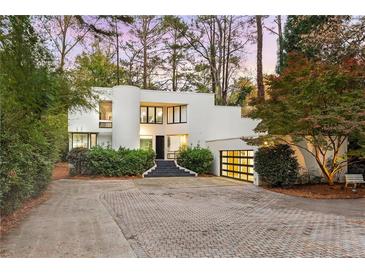 Modern white house with a large garage and stone steps at dusk at 780 Crest Valley Dr, Atlanta, GA 30327