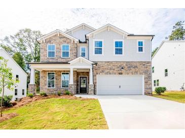 Two-story home with stone and shingle accents, a two-car garage, and a landscaped lawn at 701 Crossroad Ct, Powder Springs, GA 30127