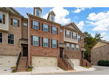 Brick front exterior of a charming townhome with a two-car garage and lush landscaping at 3135 Boldmere Se Trl, Smyrna, GA 30080