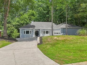 Ranch home with gray exterior, landscaping, and a driveway at 1674 Rocky Top Sw Dr, Lilburn, GA 30047