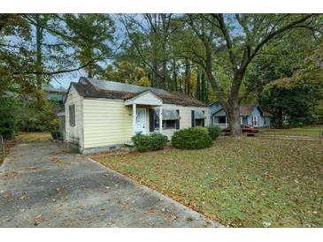 Yellow house with a small front yard and a driveway, needing some renovations at 3074 Delowe Dr, Atlanta, GA 30344