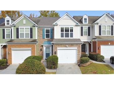 Three-unit townhome building with stone and siding, two-car garages, and landscaping at 247 Kigian Trl, Woodstock, GA 30188