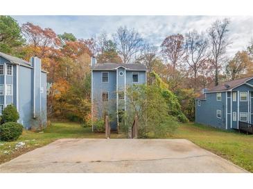 Three-story townhome with a gray exterior, situated on a grassy lot with trees at 4480 Joseph Dr, Snellville, GA 30039