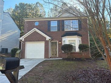 Two-story brick home with attached garage and landscaping at 7069 Ravenwood Ln, Lithonia, GA 30038