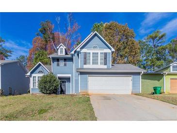 Two-story house with blue siding, white garage door, and landscaping at 6016 King Way Walk, Lithonia, GA 30058