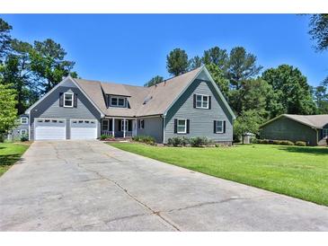 Gray two-story house with three-car garage and landscaped lawn at 4481 Nantucket Sw Dr, Lilburn, GA 30047