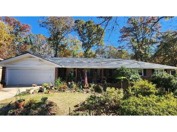 Brick ranch home with attached garage, mature landscaping, and a spacious front yard at 2479 Landeau Cir, Tucker, GA 30084
