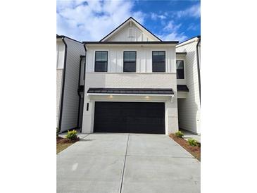 Two-story home with white brick exterior, black garage door, and landscaping at 1934 Westwind Street (Lot 136), Lawrenceville, GA 30043