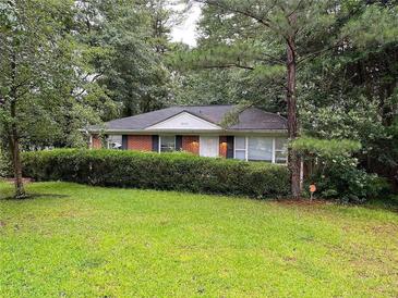 Brick ranch home with a well-manicured lawn and lush green hedge at 2110 Dellwood Pl, Decatur, GA 30032