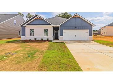 Two-toned house with white brick and blue siding, featuring a white two-car garage at 231 Orwell Dr, Social Circle, GA 30025