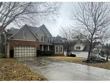 Two-story house with brick and siding, a large driveway, and mature trees at 1030 Silver Thorne Dr, Loganville, GA 30052