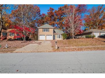 Beige two-story house with two-car garage and autumn trees at 2840 Trotters Pointe Dr, Snellville, GA 30039