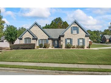 Brick home with gray shutters, well-manicured lawn, and a paved driveway at 1390 Creek Pointe Circle, Lawrenceville, GA 30043