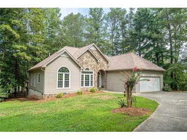 Ranch style home with stone accents and a two-car garage, nestled amongst lush greenery at 123 Wildwood Dr, Temple, GA 30179