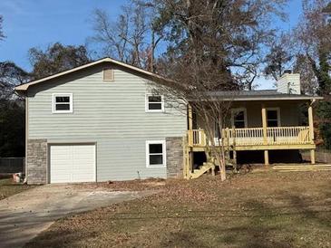 Ranch style home with new gray siding, attached garage, and a spacious deck at 488 Village Run, Lawrenceville, GA 30046