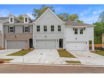 Two-story townhome with gray and white brick exterior, two-car garage, and landscaped front yard at 687 Sunstone Ln, Lawrenceville, GA 30043