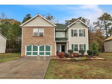 Two-story brick home with green accents, a large driveway, and landscaping at 3210 Avondale Pkwy, Powder Springs, GA 30127