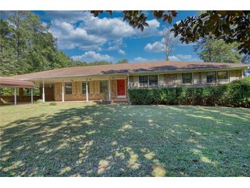Charming single-Gathering home with a carport, lush green lawn, and mature trees at 11790 Brown Bridge Rd, Covington, GA 30016