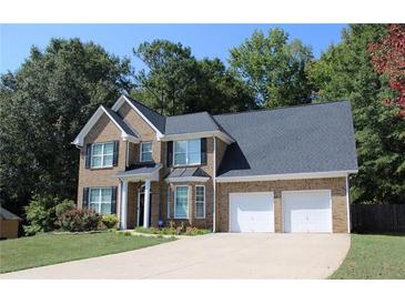 Charming two-story brick home with a three-car garage and landscaped yard at 242 Greenland Dr, Mcdonough, GA 30253