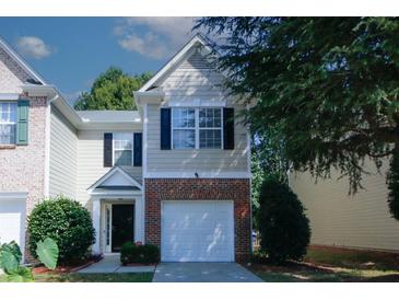 Tan two-story townhome with a white garage door and landscaping at 392 Parc River Blvd, Lawrenceville, GA 30046