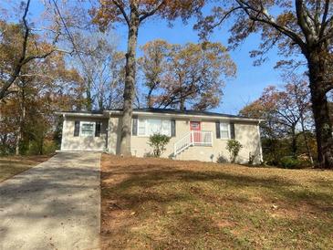 Updated ranch home with a red door and driveway, nestled amongst mature trees at 2490 Brentwood Rd, Decatur, GA 30032