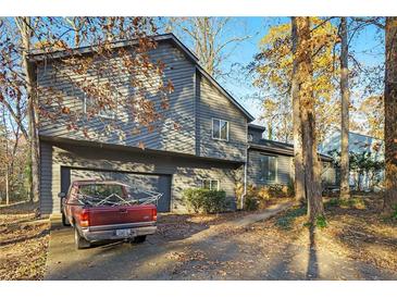 Gray two-story house with attached garage, nestled among tall trees at 5042 Post Road Trl, Stone Mountain, GA 30088