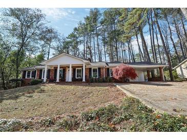 Brick ranch home with white columns, landscaping, and a long driveway at 2426 Shallowford Ne Rd, Atlanta, GA 30345