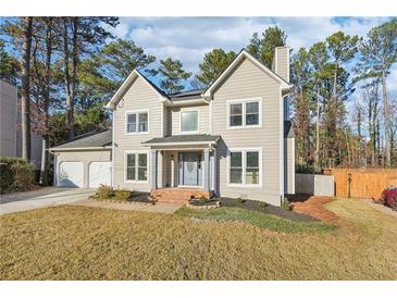 Two story house with beige siding, attached garage, and manicured lawn at 6495 Bennington Dr, Tucker, GA 30084