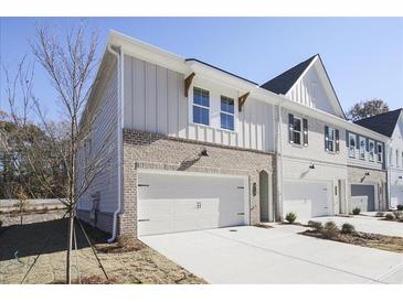Two-story townhome with brick and siding exterior, attached garage, and landscaping at 913 Agate Ln, Lawrenceville, GA 30043