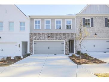 Two-story townhome with gray and white exterior, two-car garage, and landscaping at 905 Agate Ln, Lawrenceville, GA 30043