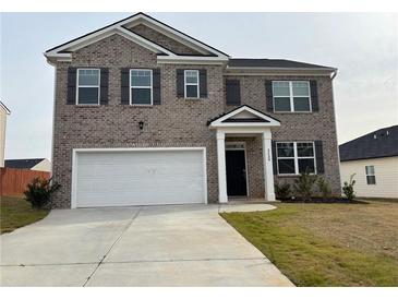 Two-story brick home with a white garage door and landscaping at 2125 Waycross Ln, Dacula, GA 30019