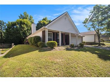 Brick and white sided house with a two-car garage and manicured lawn at 5955 Raventree Ct, Atlanta, GA 30349