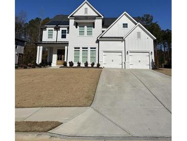 Two-story white farmhouse with black accents, three car garage, and manicured lawn at 2004 Stonecreek Dr, Woodstock, GA 30188