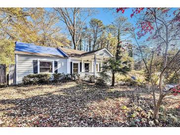 Quaint home with covered front porch, tarp on roof, and fall foliage at 1882 Brannen Se Rd, Atlanta, GA 30316