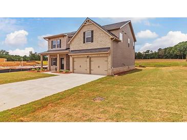 Two-story brick house with two car garage and landscaped lawn at 1621 Fuma Leaf Way, Mcdonough, GA 30253