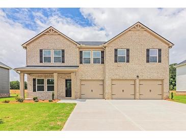 Two-story house with light brick exterior, three-car garage, and landscaped lawn at 311 Bianca Way, Mcdonough, GA 30253