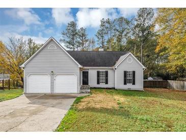 Gray house with two-car garage and landscaped yard at 1299 Paddocks Way, Powder Springs, GA 30127