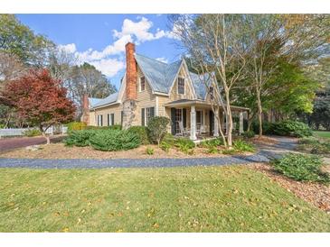 Charming two-story home with a front porch, rocking chairs, and a landscaped yard at 7865 Nesbit Ferry Rd, Sandy Springs, GA 30350