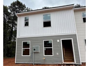 Two-story townhome with gray and white siding, featuring multiple windows and a wooden staircase at 7272 Crestside Dr # 62, Austell, GA 30168